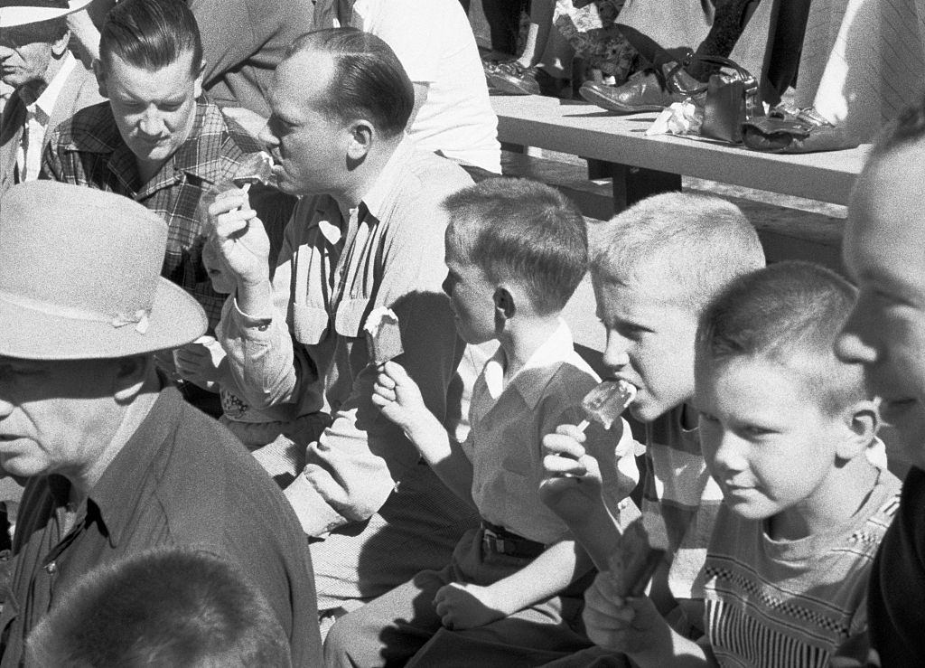 Men and boys who eat ice cream during a Jaycee Little League baseball game between the Kinsmen and the Gyros at the Hillcrest Park, Vancouver, 1954.