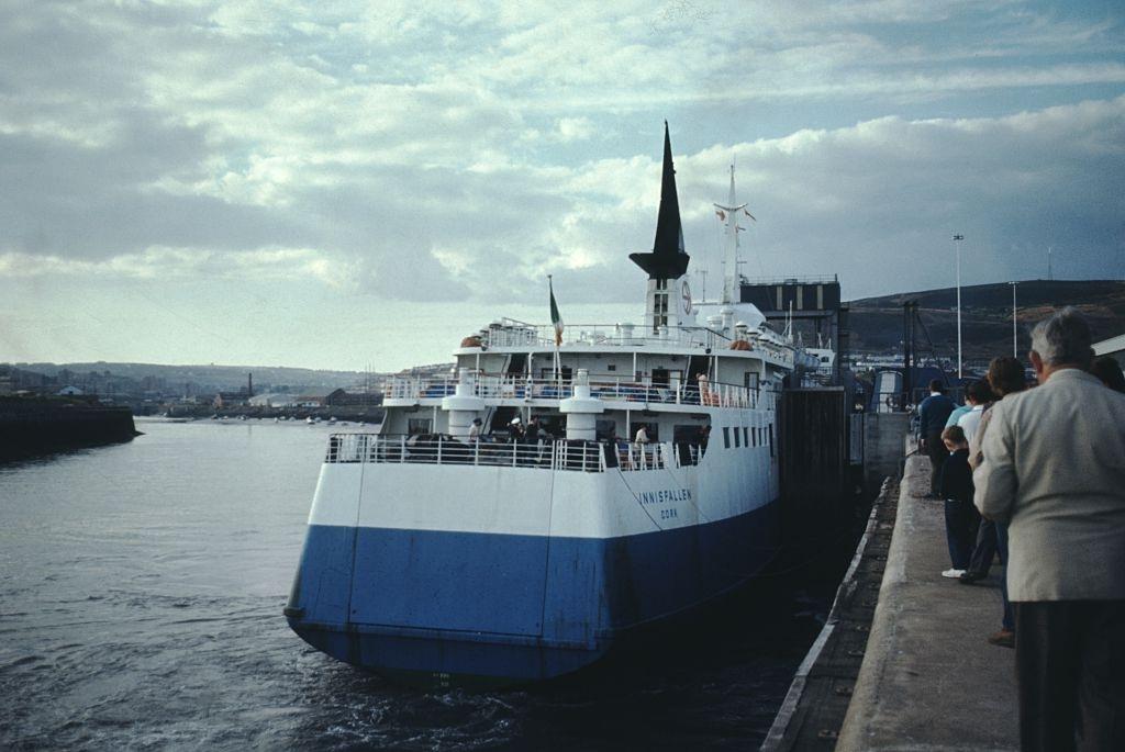 Ferry to Innisfallien pulling up to a dock, tourists preparing to embark, on a dreary, overcast day, Ireland, 1960.