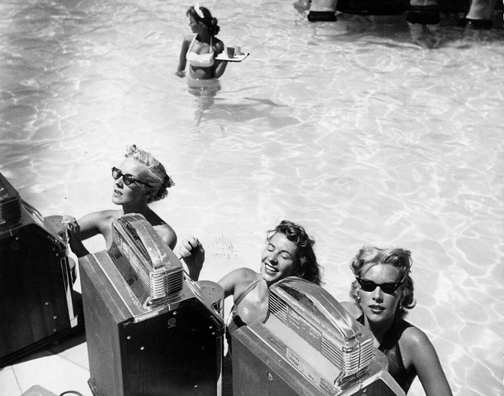 Three women play the slot machines at a swimming pool casino in the Sands Hotel, Las Vegas, 1965