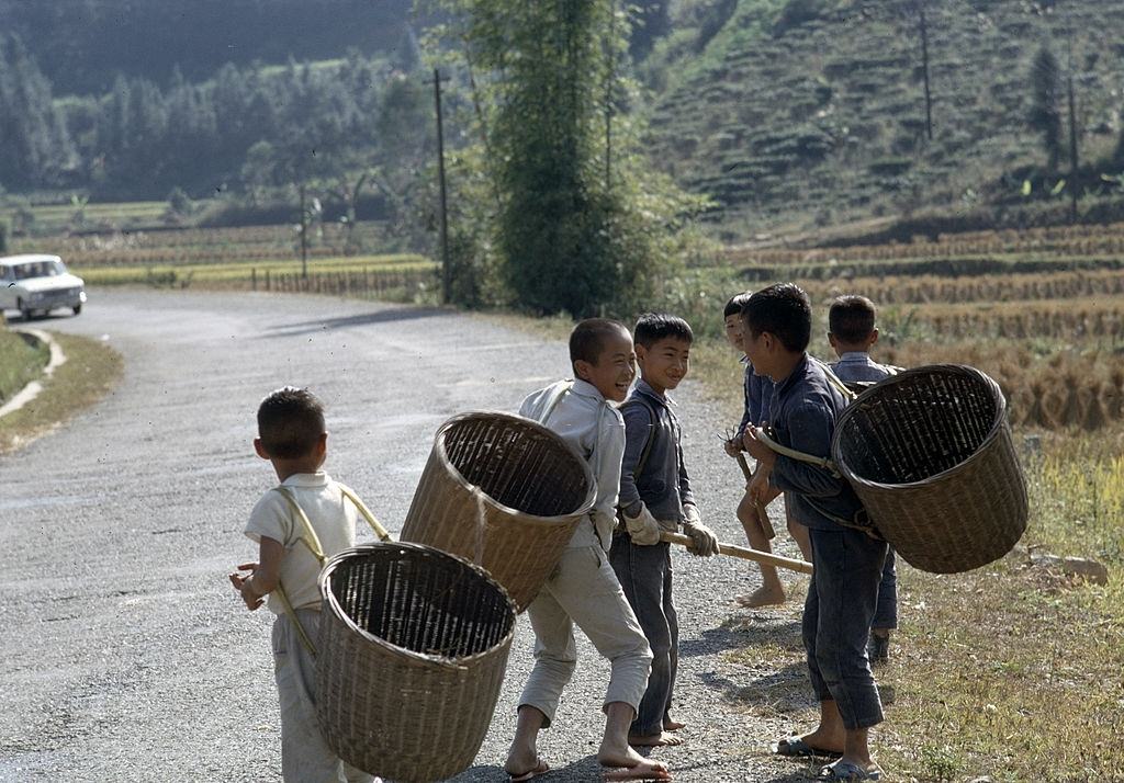 Children at the roadside, carrying baskets, Taiwan, 1969.