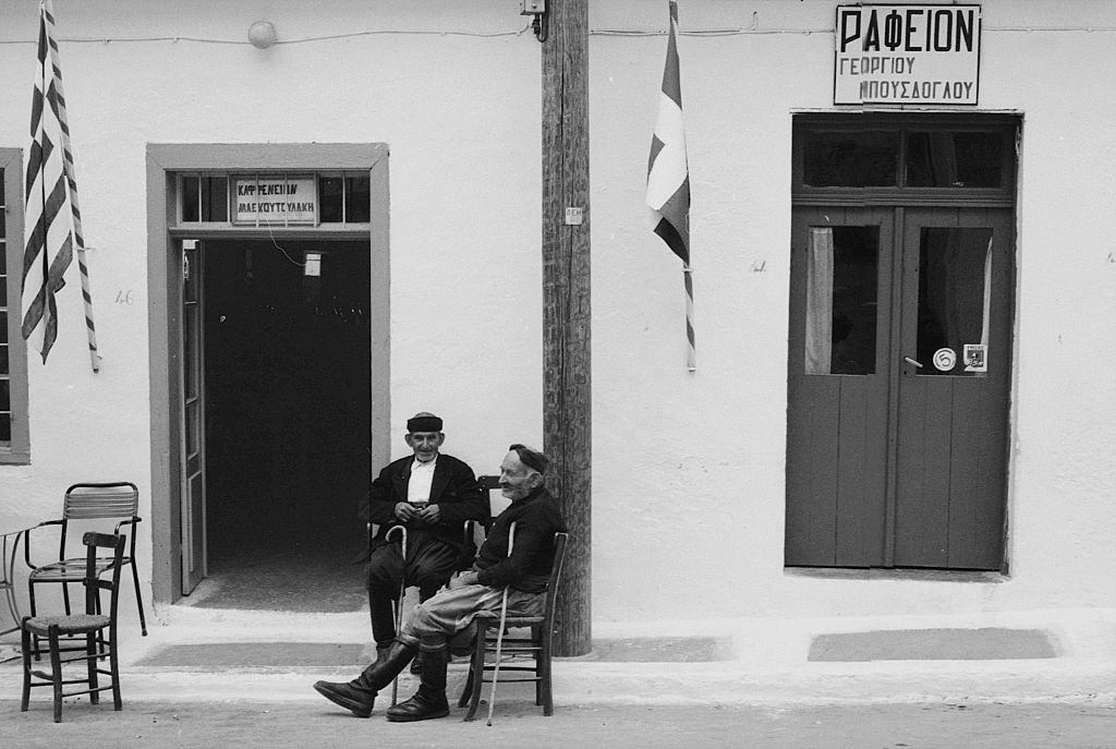 Two old men sitting in the street in a Greek island. Greece, 1970s