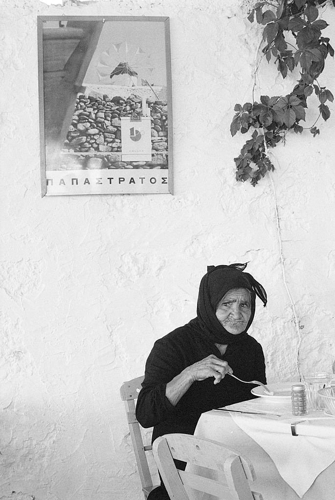 An old woman eating seated in a restaurant. Greece, 1970s