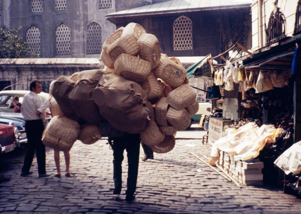 A boy carries stacks of woven baskets on his back outside the Spice Bazaar known as Misir Carisi, Istanbul, 1971.