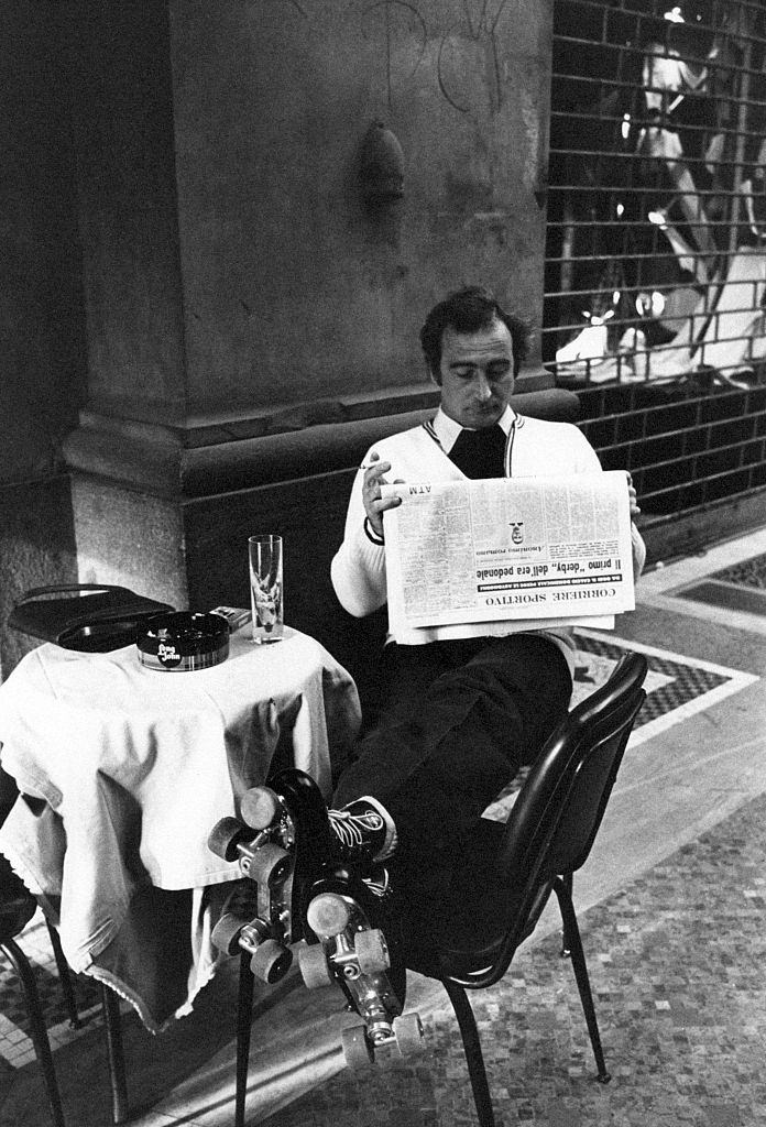 A man in roller skates reading a page from Corriere sportivo seated at the table in a caf on the first Italian walking sunday due to the oil crisis. Milan, 2nd December 1973