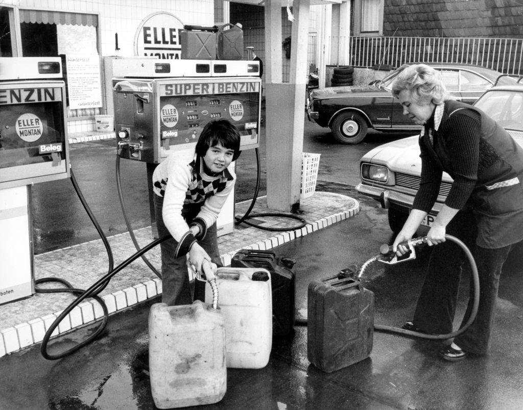 A woman and a boy fill petrol canisters with petrol at a petrol station on the 7th of November in 1973.