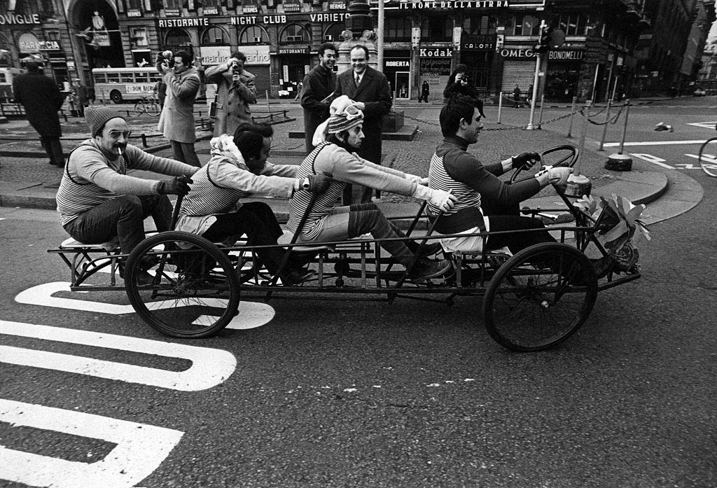 Four men on a tandem bicycle crossing Piazza del Duomo during the first Italian walking sunday due to the oil crisis. Milan, 2nd December 1973