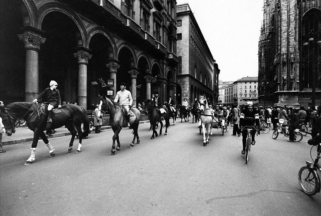 Some people riding horses, gigs and bicycles across Piazza del Duomo during the first Italian walking sunday due to the oil crisis.