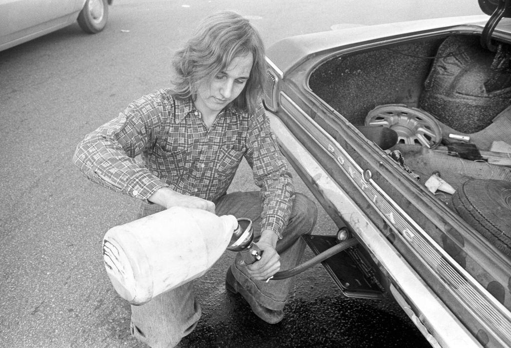 Motorist pours gas into car from jug during 'oil crisis,' Boston, Massachusetts, 1973.