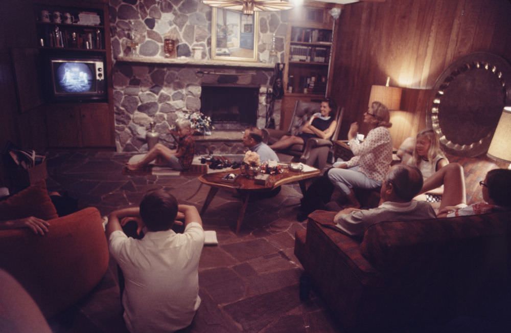 Joan Aldrin (pöttyös fehér ingben) texasi otthonának nappali szobájában, fiaival, lányával és barátaival, élő televízión keresztül figyeli a férje hold küldetését.