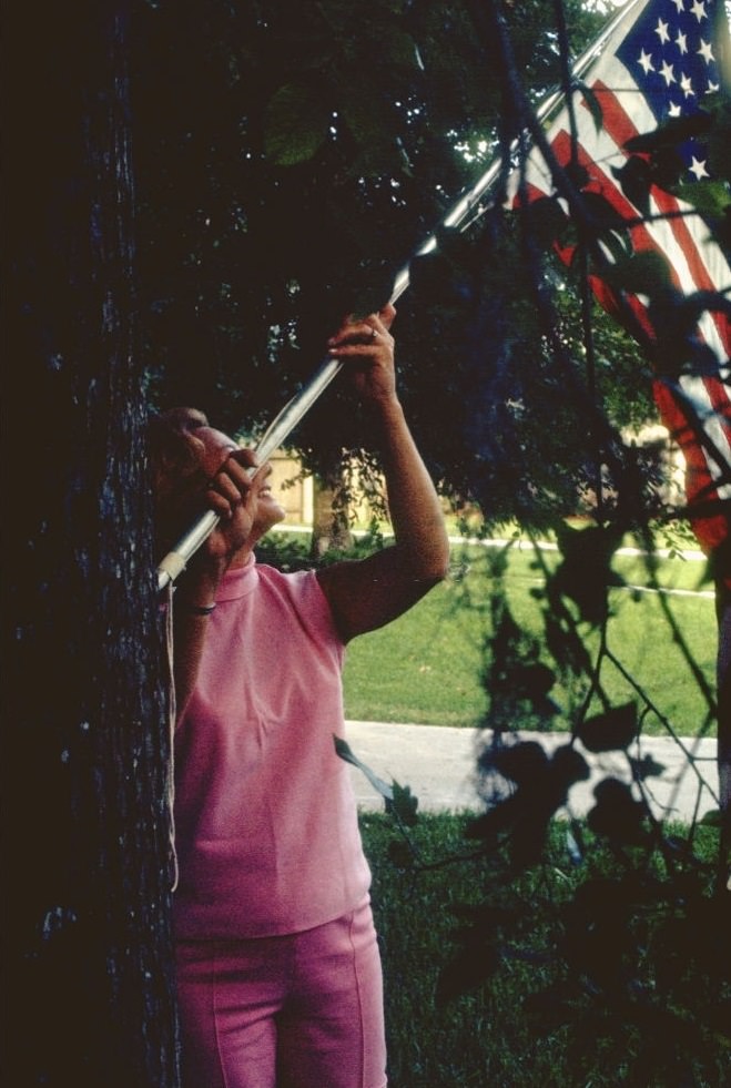 A family member of Apollo XI astronaut raising a flag, Houston, Texas, July 1969