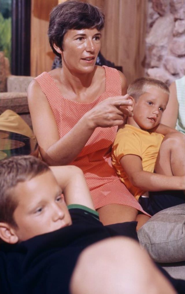 Janet Armstrong sitting on floor with her two sons, attentively watching TV at home as the lunar module lands on the moon.