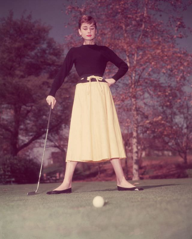 Audrey Hepburn standing on a golf course, 1955.