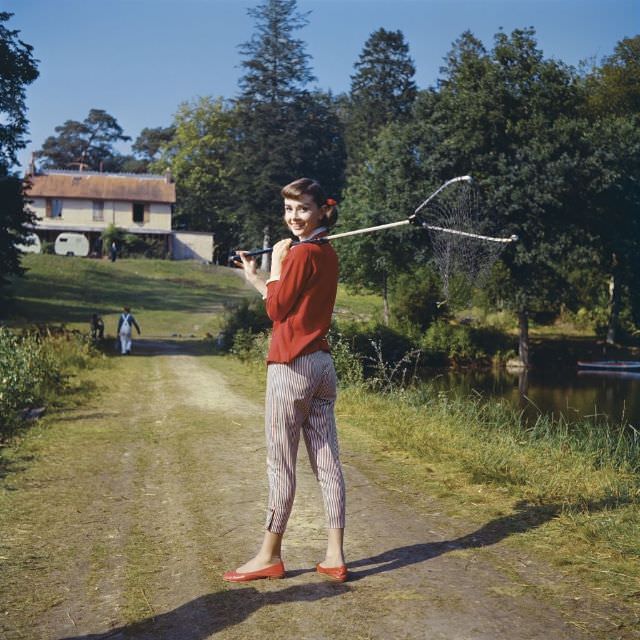 Audrey Hepburn reaching for a branch in the Bois de Boulogne, Paris, 1957.