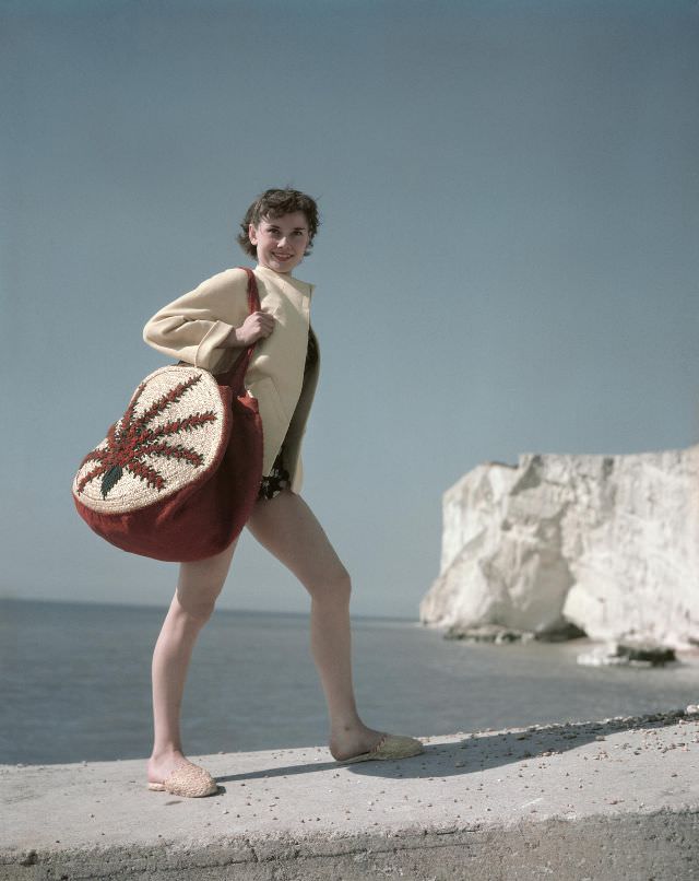 Audrey Hepburn at the seaside whilst carrying a shoulder bag, 1951.