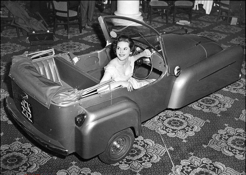 Model Gay McGregor shows off the latest 1956 model Bond Minicar three-wheeler, in London.