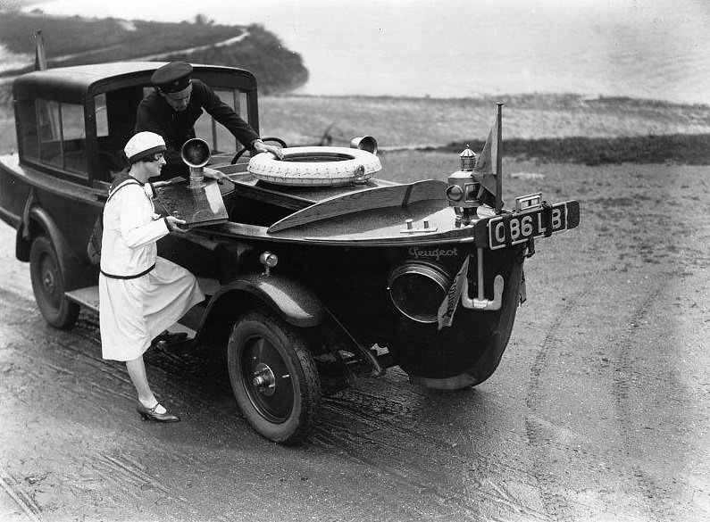 The Peugeot motor-boat car, on a river bank. The front end is shaped like the bow of a boat, the middle part like a car and it has wheels.