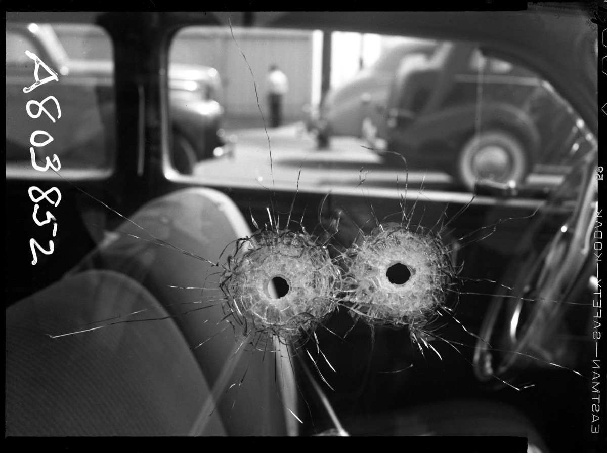 Detail of two bullet holes in car window, 1942