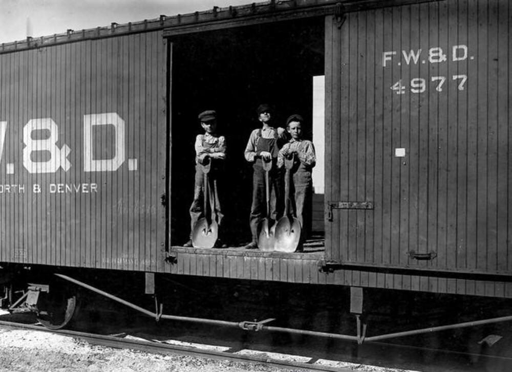 Three young boys with shovels standing in doorway of a Fort Worth & Denver train car, 1912
