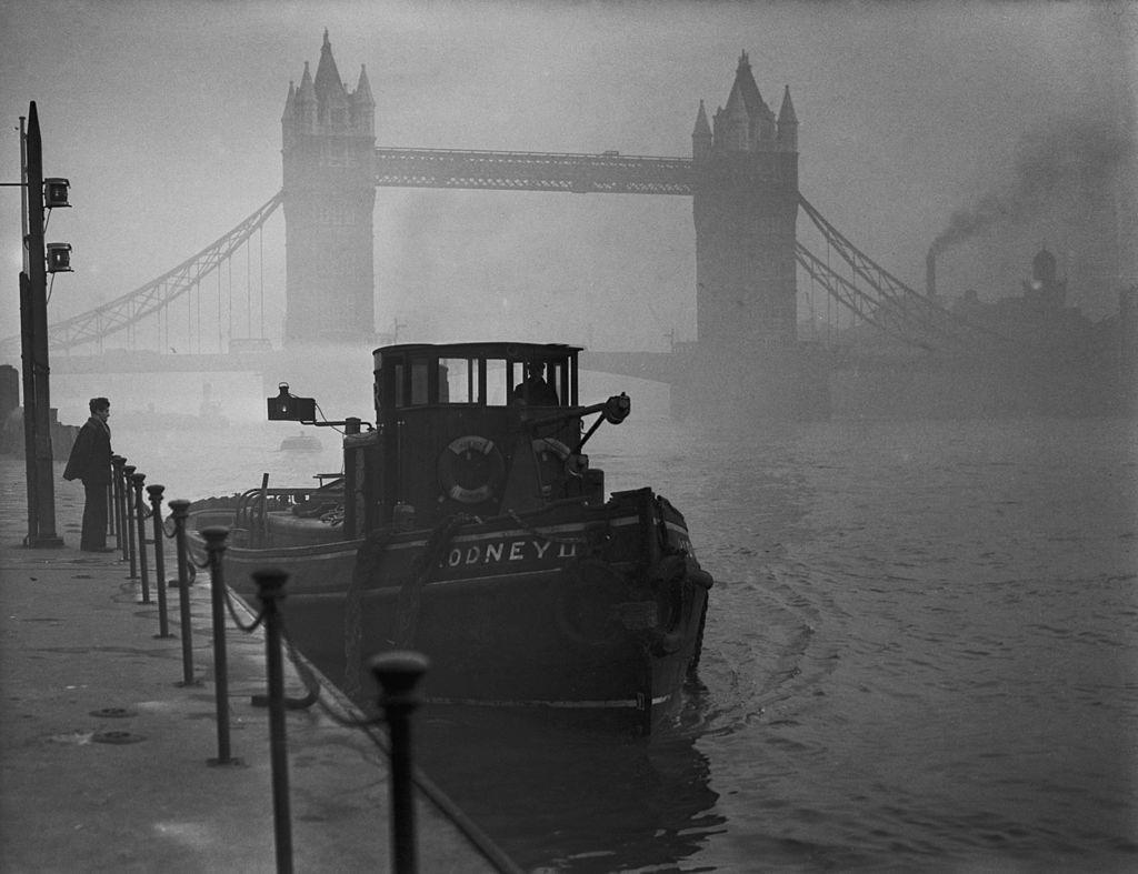 A tugboat on the Thames near Tower Bridge in heavy smog, 1952.