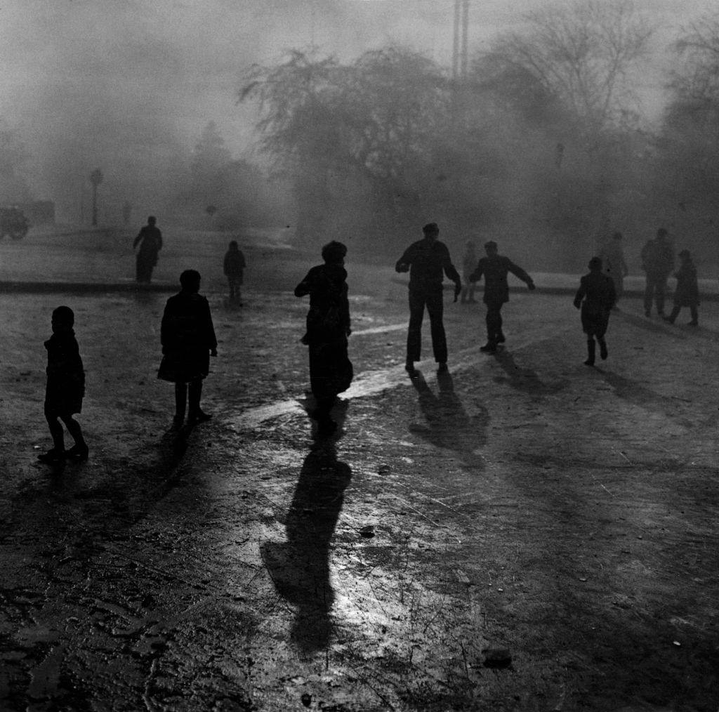 Boys sliding on the ice in the fog at Hampstead Heath ponds during the Great Smog of London, 1952.
