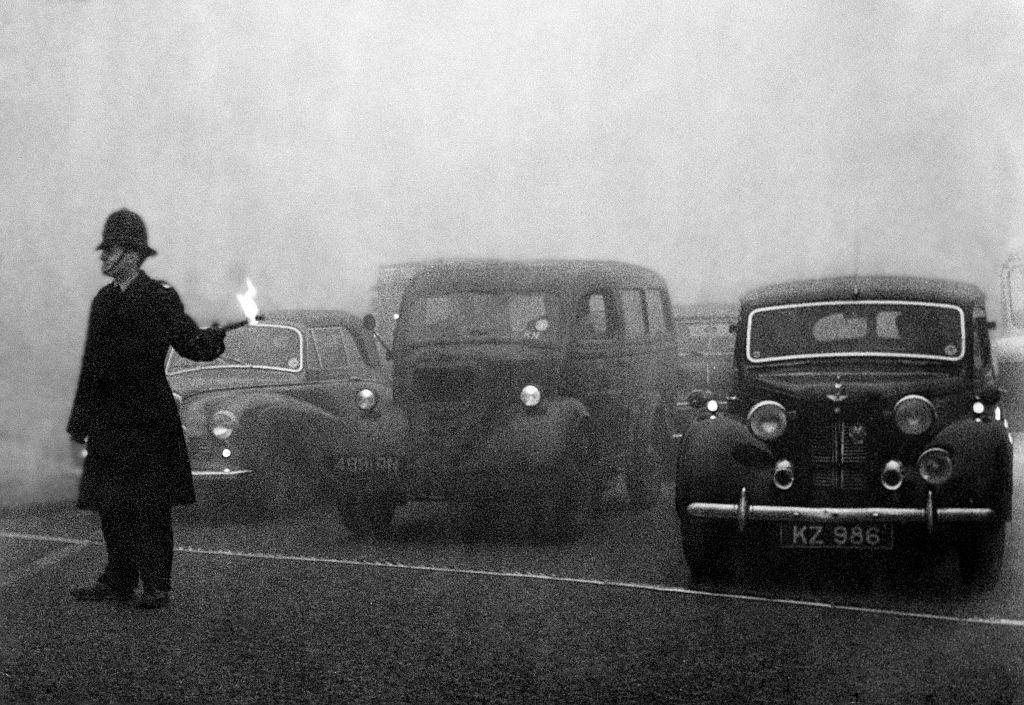 Policeman on point duty using flares to guide the traffic during a heavy smog in London. 8th December 1952