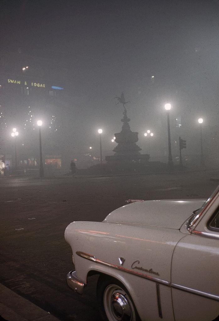 View of a parked car near the Statue of Eros in Piccadilly Circus, London, 1952.