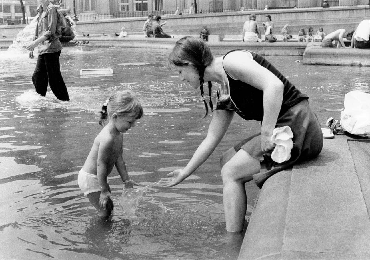 A woman and child splash around in the fountains at Trafalgar Square