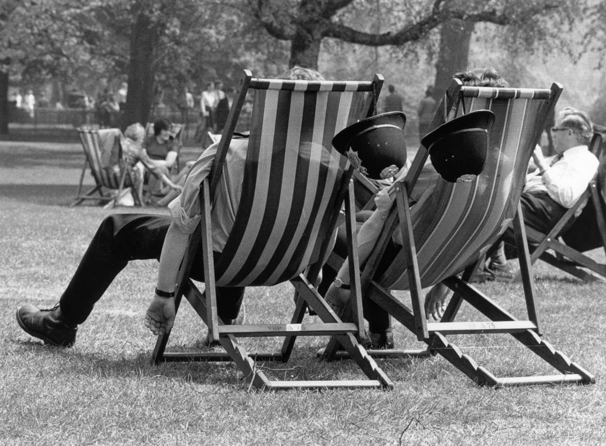 Two London policemen take the weight off their feet during the heatwave, whilst patrolling the park