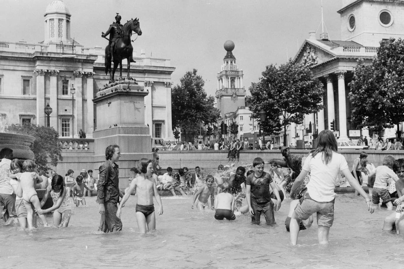 People enjoy the cool water in the fountains at Trafalgar Square