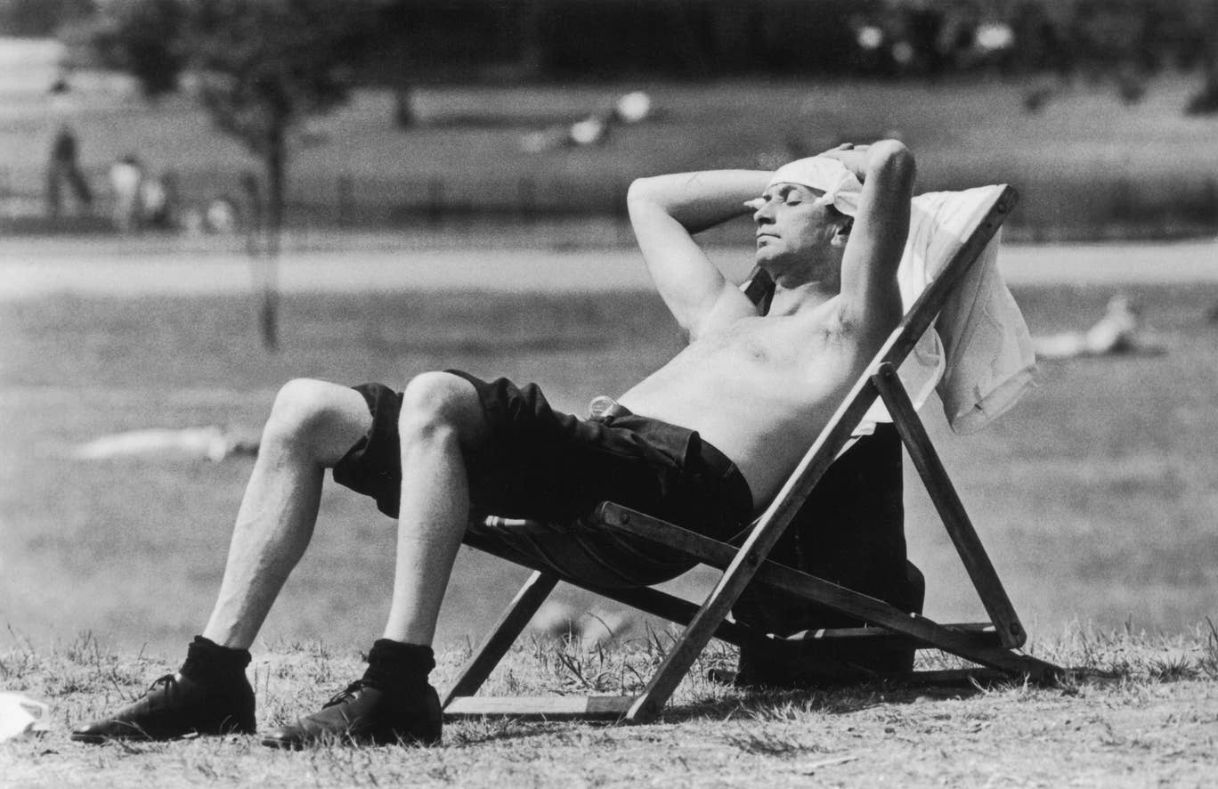 A Londoner sunbathing in Kensington Gardens with a knotted handkerchief protecting his head from the sunshine