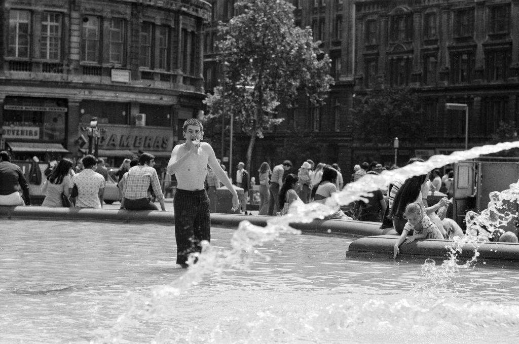 As the temperatures soared, the cool fountains in Trafalgar Square were even more tempting to the people sitting around them, inspire of the law which says it is illegal to bathe in them, 13th June 1976.