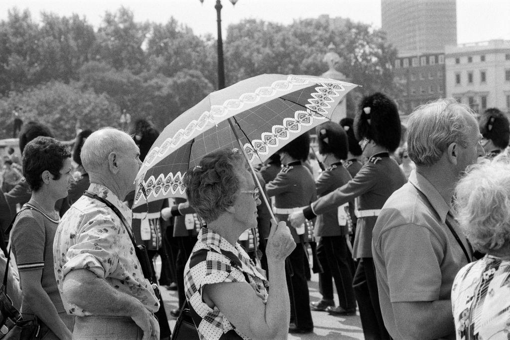 Changing of the Guard in London today. An umbrella serves as a sun-shade for a spectator, 8th June 1976.
