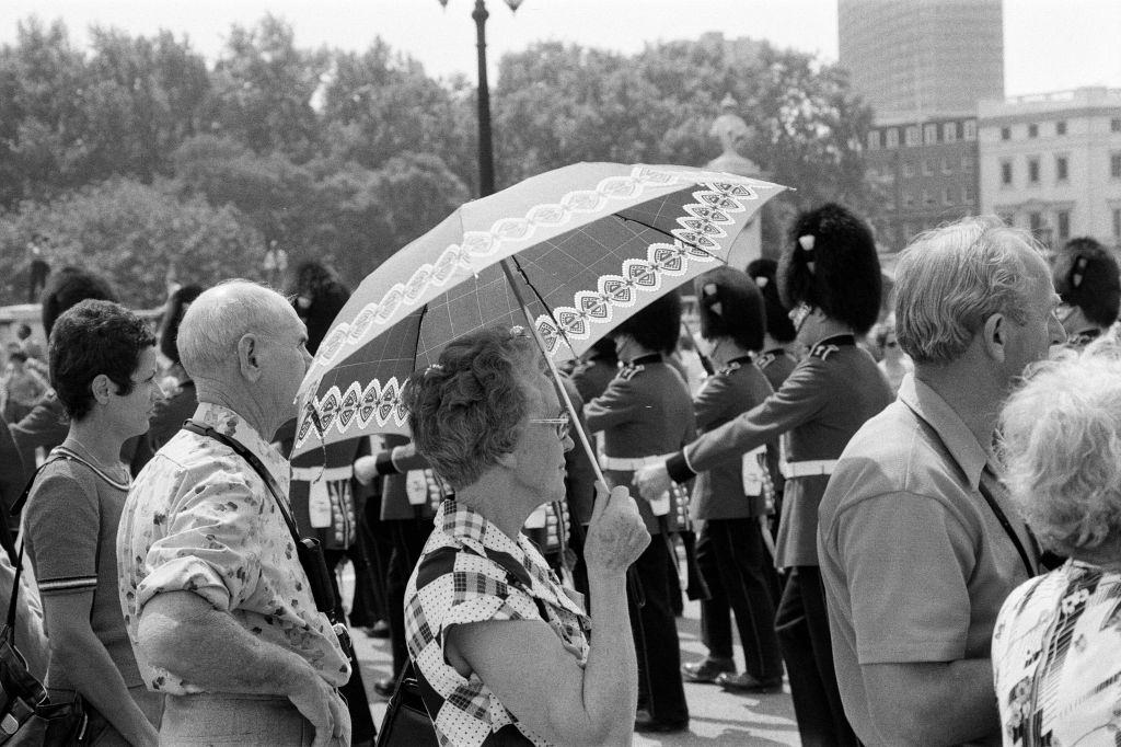 Changing of the Guard in London today. An umbrella serves as a sun-shade for a spectator, 8th June 1976.