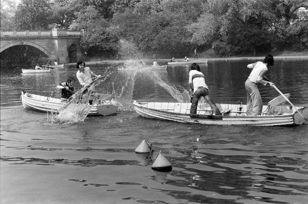 Keeping cool in the Serpentine, rowers enjoy a water fight, 7th May 1976.