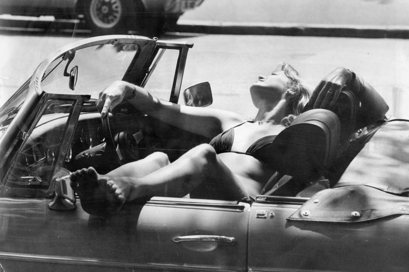 A woman soaks up the sunshine in a convertible car