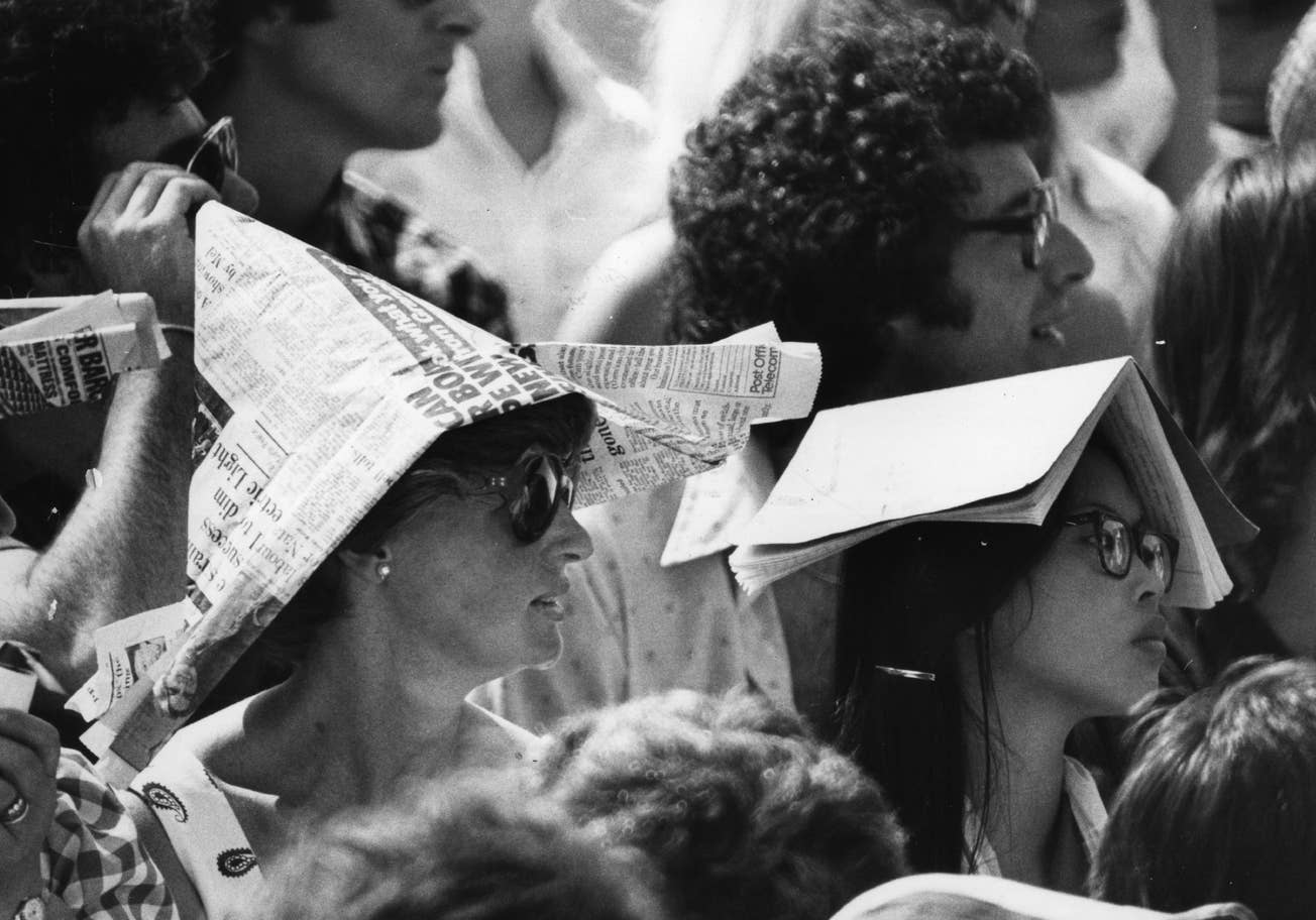 Spectators at Wimbledon Tennis Championships protect themselves from the sun wearing newspaper hats