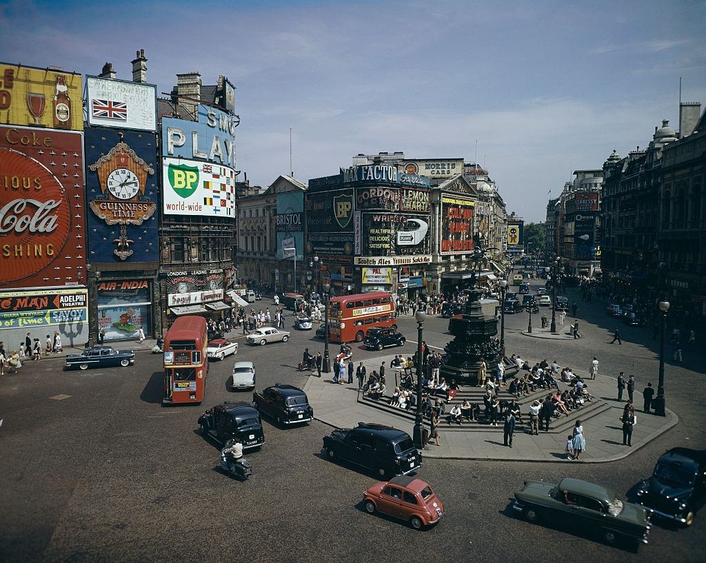 View of Piccadilly Circus in London with cars and buses passing the Shaftesbury Memorial fountain and statue of Eros, 1962.
