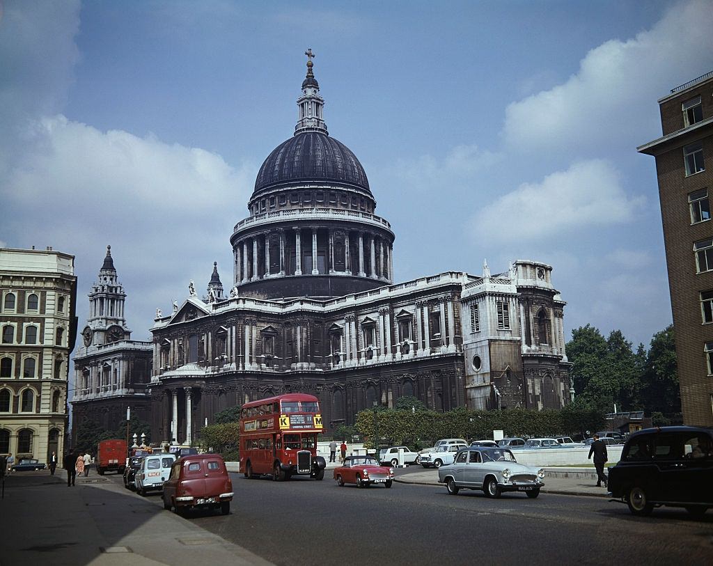 St Paul's Cathedral in London with cars and a bus passing through St Paul's churchyard and along Cannon Street, 1962.