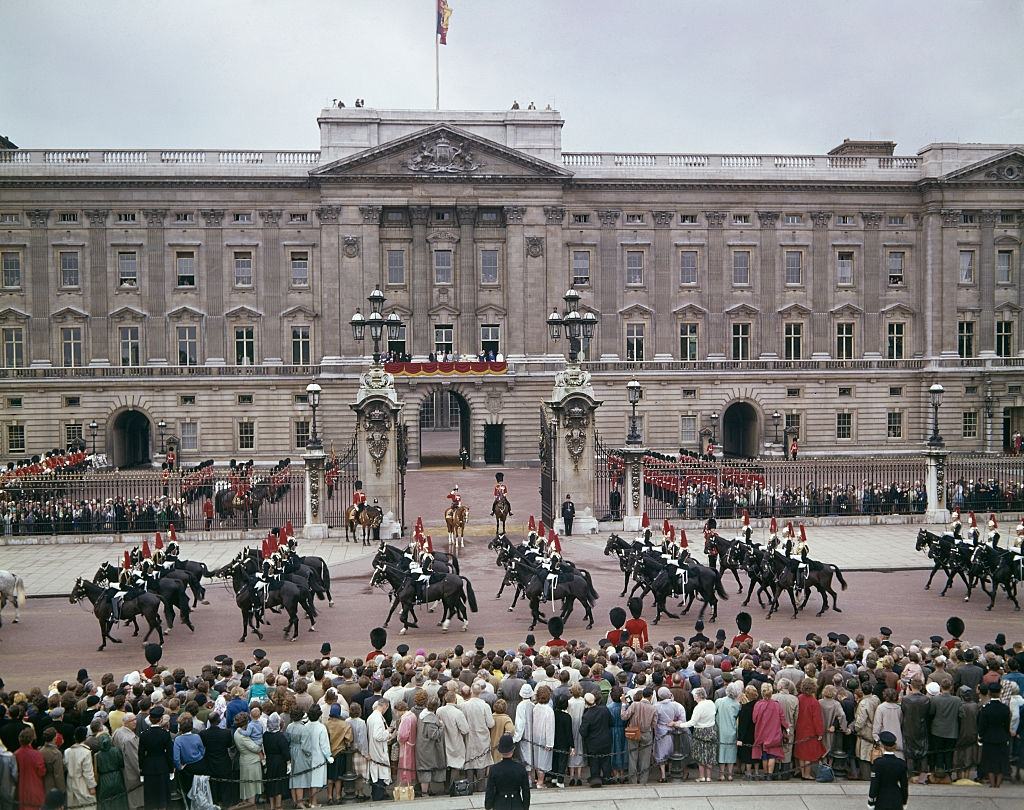 Elizabeth II saluting members of the Household Cavalry as they march past the gates of Buckingham Palace during the Trooping the Colour ceremony in London, 1962