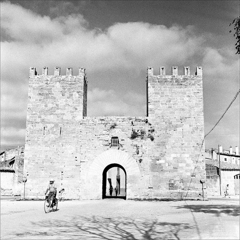 Man with a bicycle at the door from the wharf of Alcúdia, 1956