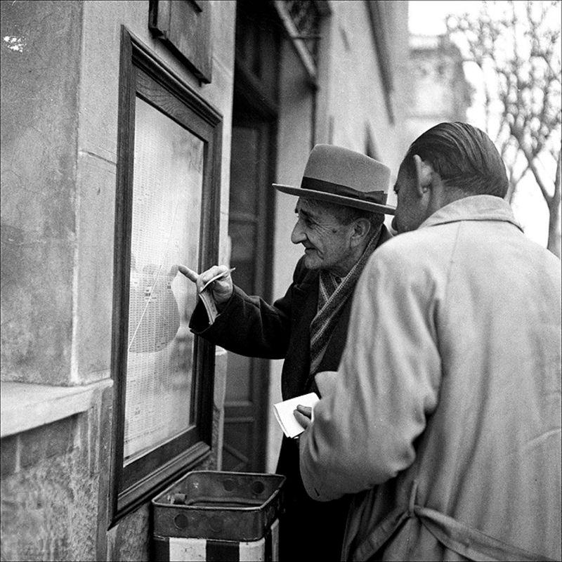 Two men looking at lottery results, 1957