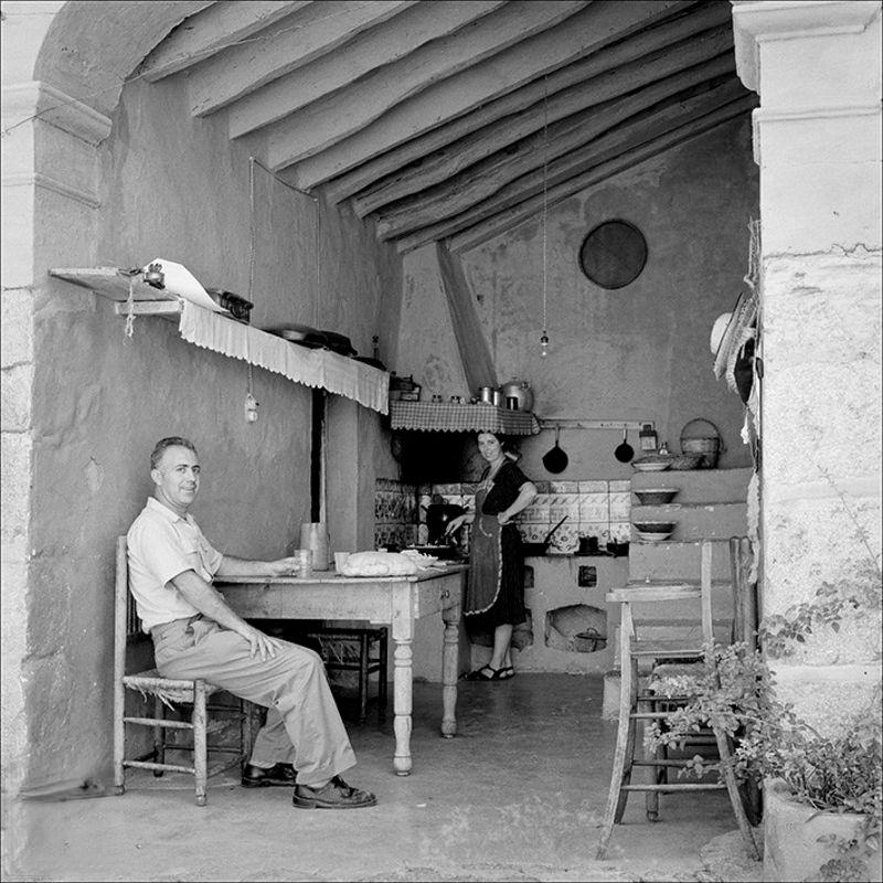 Traditional open kitchen with seated man and woman in the kitchen background, 1958