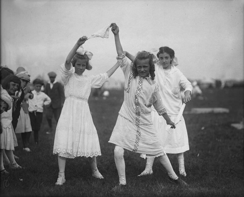 Three girls with handkerchief at Buttonwood Park, playground outing, 1915