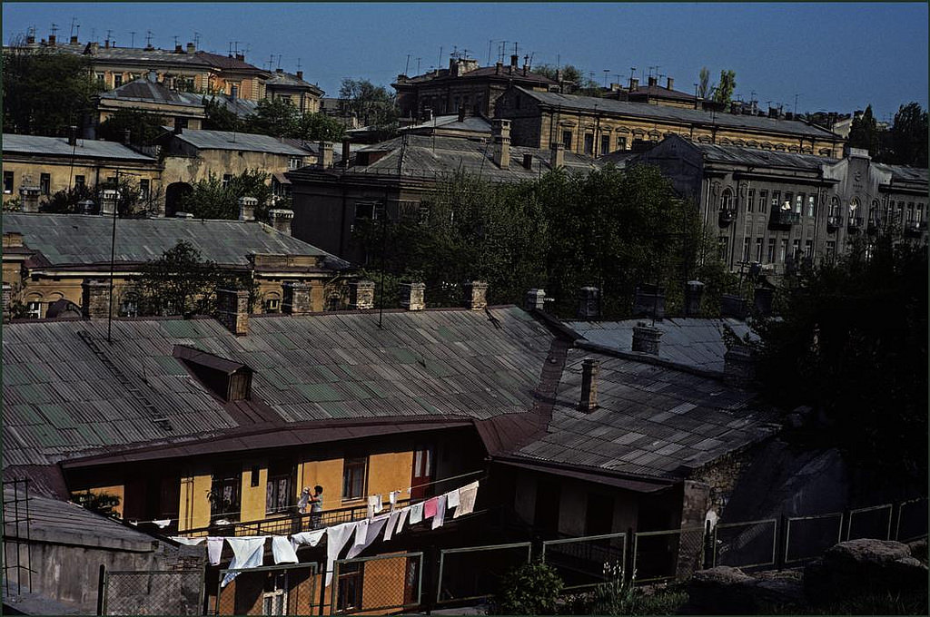 Woman hanging out washing in a patch of sunshine in an overall view of the city.