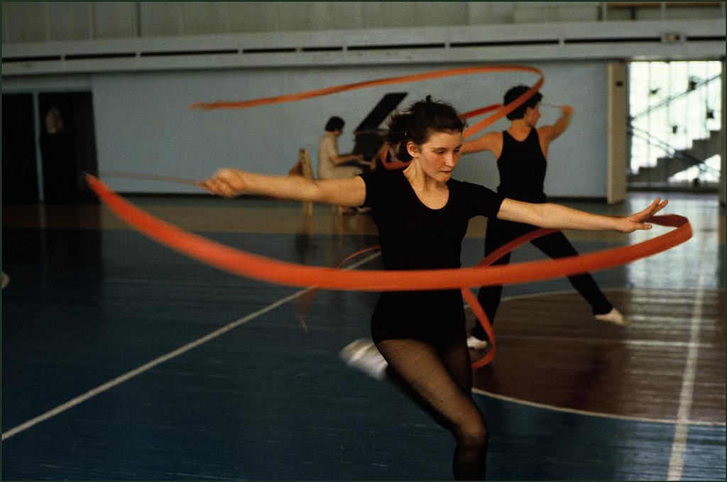 Dance gymnasts twirling ribbons in time to piano music.