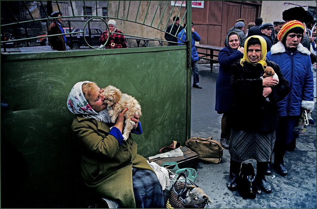A woman cuddles a dog she hopes to sell at the pet market whilst others look on.