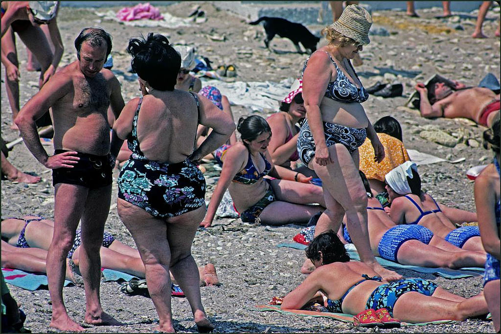A couple of stout ladies enjoy the sun amongst the beach crowd.