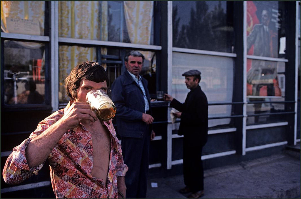 Men buying beer from a kiosk to drink on the street in the city.