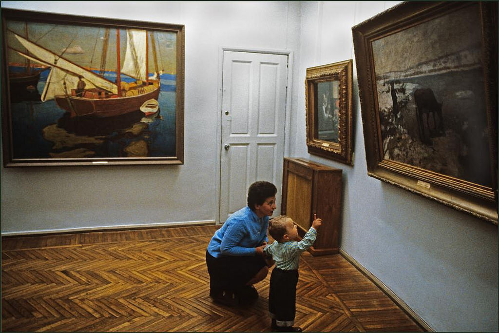 A mother explaining to her young son the contents of a painting in the museum.