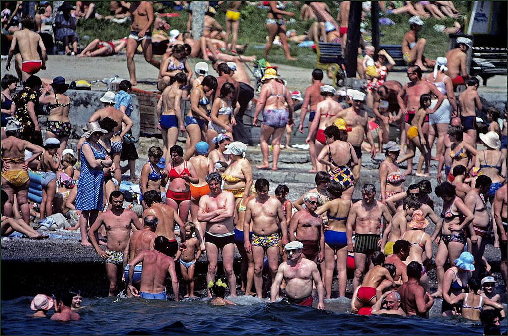 The crows spills over into the water on a crowded beach.